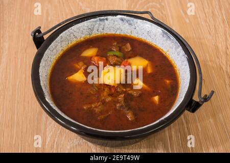 Hungarian Beef Goulash or Gulyas Soup or Stew Served in a Small Cauldron with Potatoes, Meat, Paprika and Pepper Stock Photo