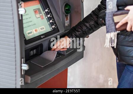 Female hands hold a plastic bank credit card, use an ATM machine to withdraw money Stock Photo