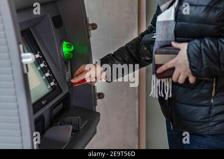 Closeup woman hand inserting debit card into an ATM machine Stock 