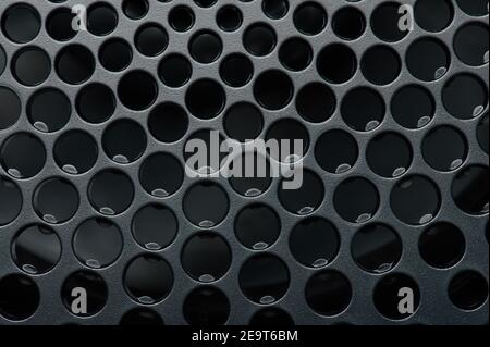 Grid of holes in black surface macro close up view Stock Photo
