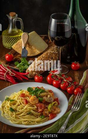 Spaghetti with shrimps, cherry tomatoes and spices on wooden background. Food background. Stock Photo