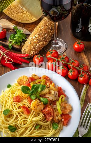 Spaghetti with shrimps, cherry tomatoes and spices on wooden background. Food background. Top view. Stock Photo