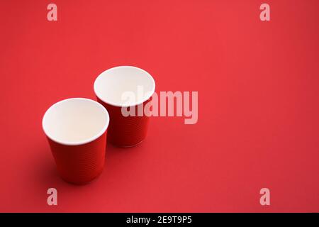 two red cardboard empty coffee glasses. two paper cups on red background. Stock Photo