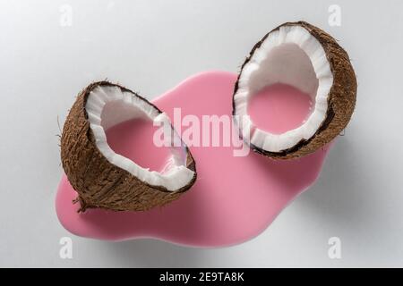 Creative layout made of coconut in half with pink milk pouring. Minimal food concept. Stock Photo