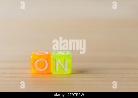 ON text with color letters cubes on wooden background. Minimal concept. Stock Photo