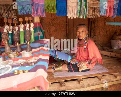 An old woman from karen hill tribe posing weaving cloth. He also sells souvenirs and woven fabric from his tribal handicrafts Stock Photo