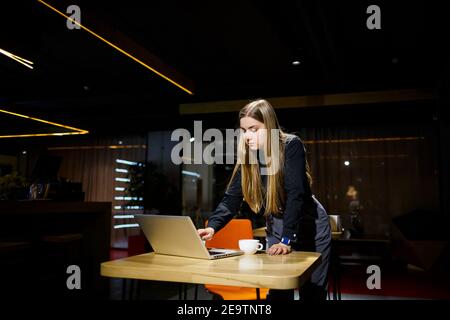 Normal working day of modern woman businessman. Beautiful young woman holding a cup of coffee while sitting at her workplace Stock Photo