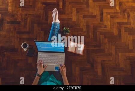 IT professional woman working from home with Laptop and Phones with a hot cup of coffee beside and a green plant
