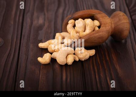 Cashew nuts in wooden scoop, on wooden background. Roasted cashew nuts. Stock Photo