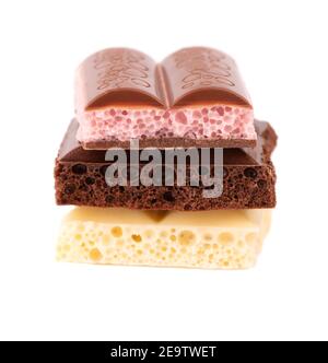 Mix of porous chocolate pieces isolated on white background. Black, white and pink aerated chocolate. Stock Photo