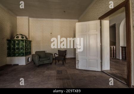 green tiled stove and armchair in an old room Stock Photo