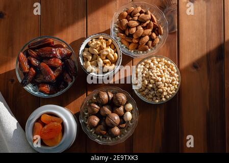 Different dried fruits and nuts under natural sunlight on wooden table. Overhead, from above Stock Photo