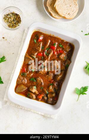 Stewed chicken livers in baking dish over light stone background. Top view, flat lay Stock Photo