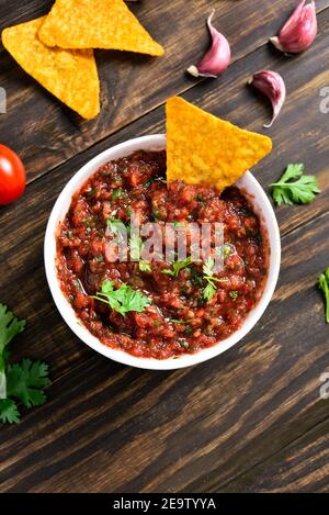 Homemade tomato salsa in bowl over wooden background. Top view, flat lay Stock Photo