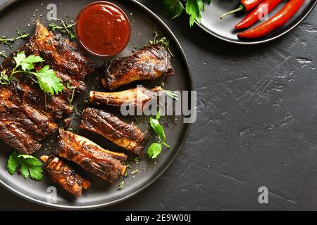 Close up view of grilled spare ribs on plate over black stone background with copy space. Top view, flat lay Stock Photo