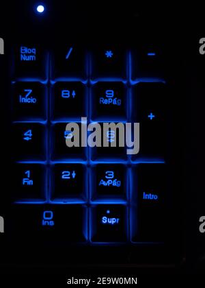 Close up numbers in a black keyboard with blue retro light. Stock Photo