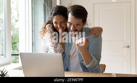 Laughing couple embracing by computer winning at sports betting Stock Photo