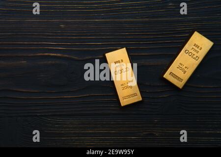 Gold bars lie on a black wooden background, two bars close-up Stock Photo