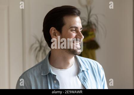 Handsome smiling bearded millennial man distracted from camera looking aside Stock Photo