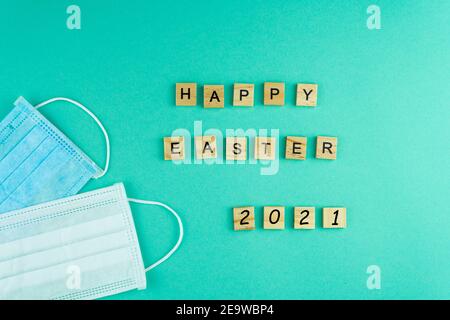 Happy Easter 2021 Medical masks. The phrase is laid out in wooden letters. View from above. Motivation. Medical masks. Mask. Copy space. Postcard for Stock Photo