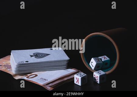 Card deck on euro banknotes, and a poker cup with dices isolated on a black background Stock Photo