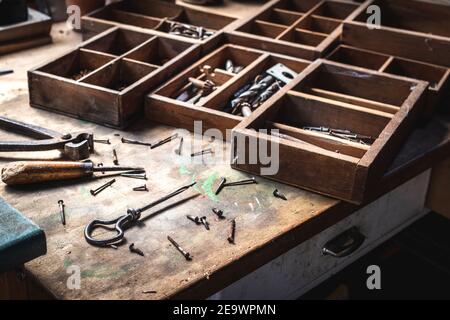 Carpentry workshop. Group of messy vintage hand tools on wood table. Toolbox with rusty nail, bolt and drill bit Stock Photo