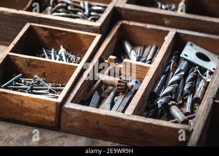 Toolbox with nail, bolt, screws and drill bit on wooden table. Rusty industrial equipment in carpentry workshop Stock Photo