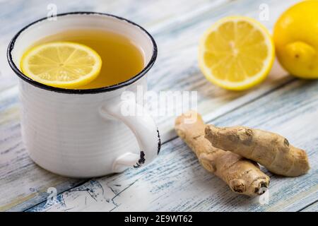 Ginger tea with slice lemon in white mug. Healthy lifestyle concept. Hot drink in teacup and ginger root on wooden table Stock Photo