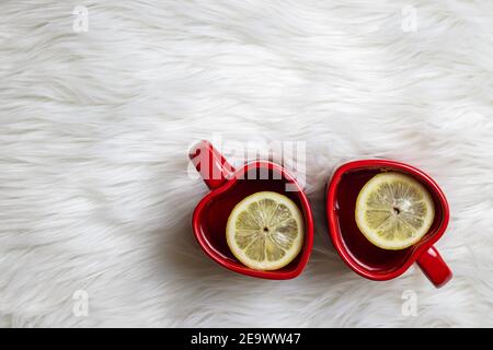 Two red heart shape tea cup with slice lemon on fur background. Home sweet home. Hot drink at valentines day Stock Photo