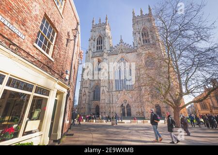 York, England - February 24 2018: Visitors to old town historic York gathering at Deansgate outside York Minster Cathedral on a sunny winter day. Stock Photo