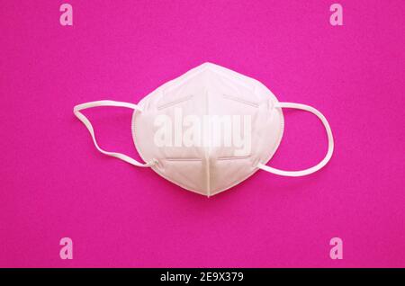 KN95 or N95 FFP2 mask for protection pm 2.5 and corona virus (COVID-19). Anti pollution mask.air face mask, N95 FFP2 mask on pink background. Stock Photo