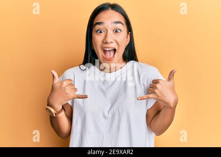 Young asian woman doing shaka sign with hands celebrating crazy and amazed for success with open eyes screaming excited. Stock Photo