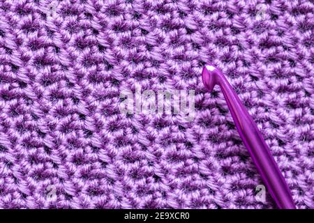 Handmade close-up simple lilac crochet pattern with crochet hook. Stock Photo