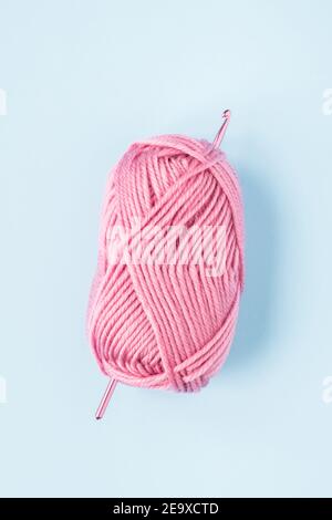 knitting pink crochet hooks and woolen thread on a blue background