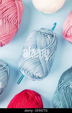 Multicolored crochet hooks with balls of yarn on a blue background. Stock Photo