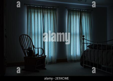 Early morning light enters through net curtains into a bedroom onto a whicker chair. Stock Photo