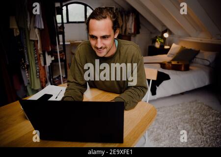 Caucasian male student studying from home typing on laptop sitting at desk in home office Stock Photo