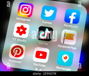 Social media app icons in folder on iPhone screen. Stock Photo
