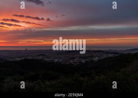 Sunrise on a spring day in the city of Barcelona. We can see the sky, with some clouds that light up like fire, with the sunlight. Mediterranean Sea. Stock Photo