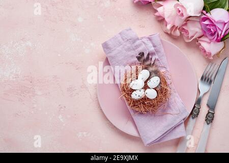 Easter spring greeting table setting with decorated with roses and nest with Easter eggs on blue color background. Top view. Space for text. Stock Photo