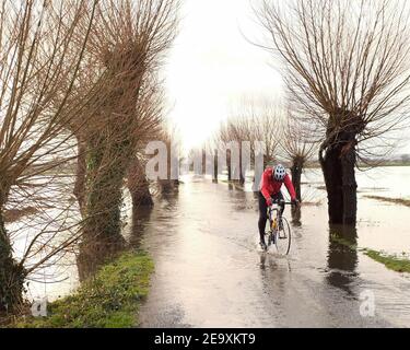 February 2021 - Cyclist riding through the flooding on the Moors at Godney near Glastonbury in Somerset, England, UK Stock Photo