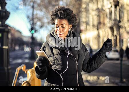 Shallow focus of a smiling African woman with short curly hair listening to music with headphones Stock Photo