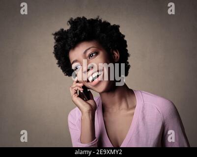 Portrait of a young African woman with short curly hair talking on the phone and smiling Stock Photo
