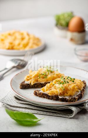 Scrambled egg sandwich with cream cheese on rye toast for breakfast on white background. Healthy breakfast or snack Stock Photo