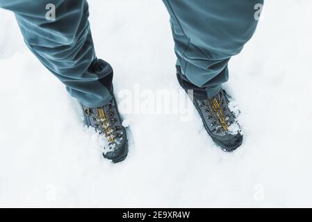From above of crop unrecognizable hiker in trekking boots standing on snowy ground in winter Stock Photo