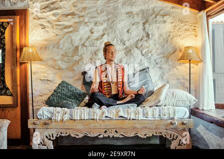 Blond man practicing meditation with closed eyes at home Stock Photo