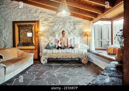 Blond man practicing meditation with closed eyes at home Stock Photo