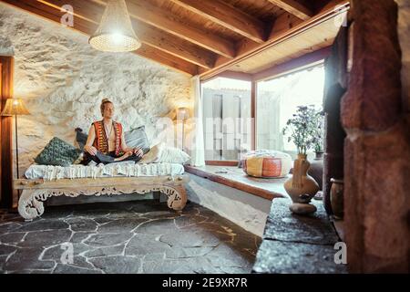 Blond man practicing meditation with closed eyes at home Stock Photo