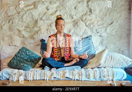 Blond man practicing meditation with closed eyes at home Stock Photo