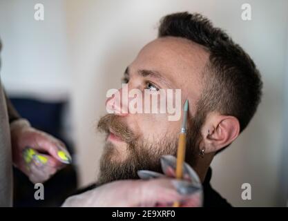 Close-up of an unrecognizable makeup artist putting makeup on a hipster man's face Stock Photo